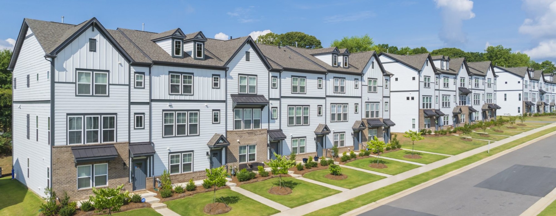 Exterior image of 3-story townhomes with landscaping and sidewalks