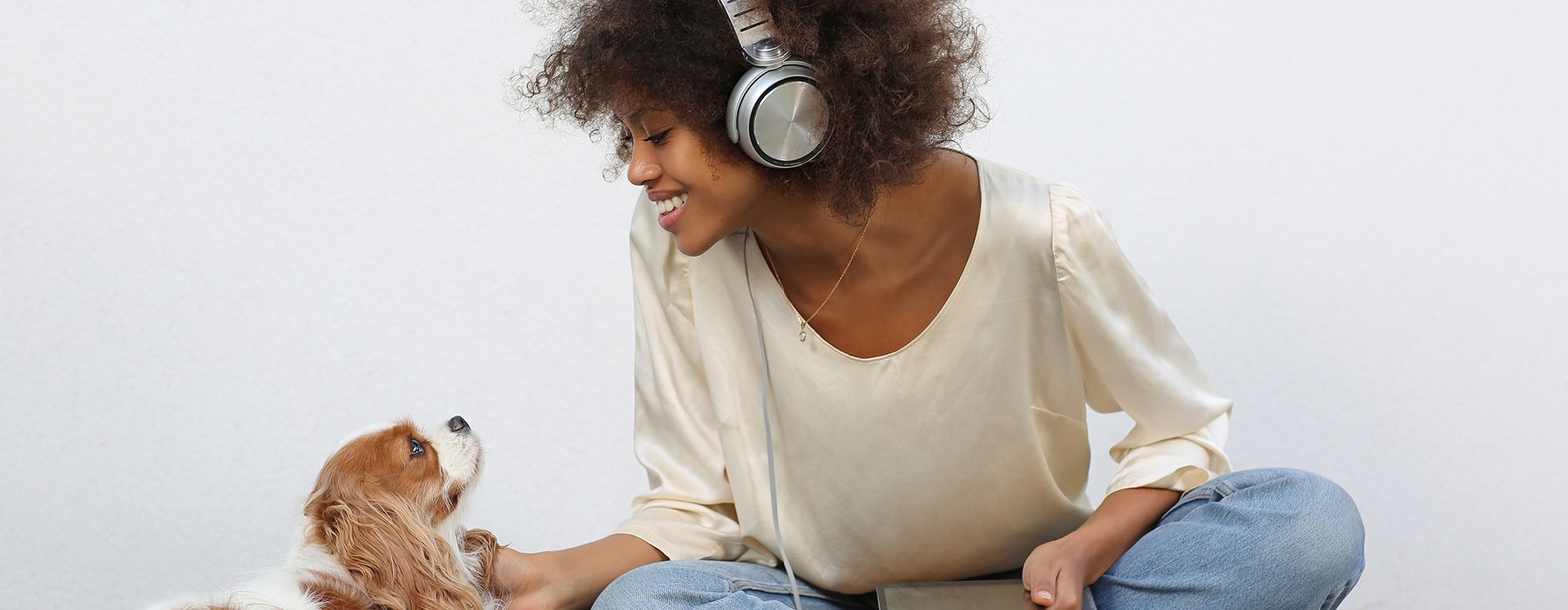woman with headphones on smiles at her puppy